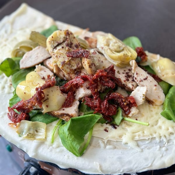 Savory crepe with chicken, sun-dried tomatoes, artichoke hearts, spinach, and melted cheese.