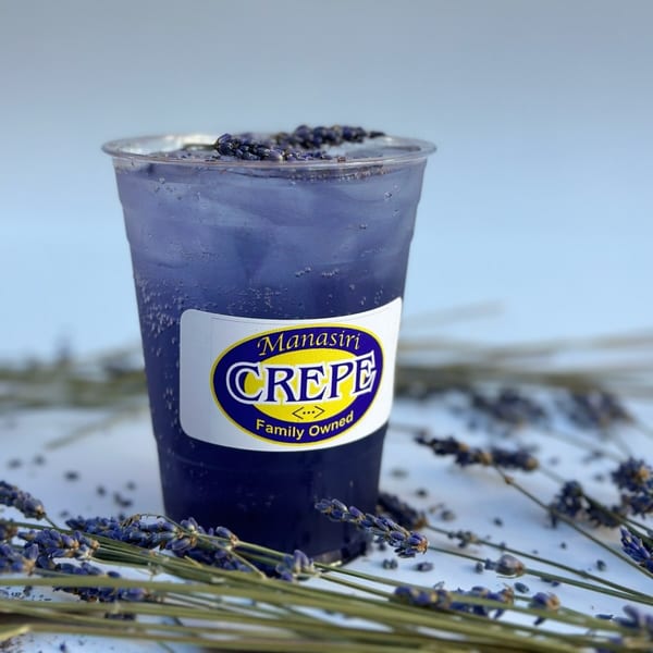 A Manasiri Crepe lavender drink in a clear cup, garnished with lavender sprigs.